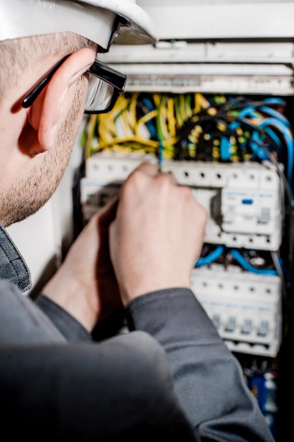 Hands working on the wiring inside a consumer unit
