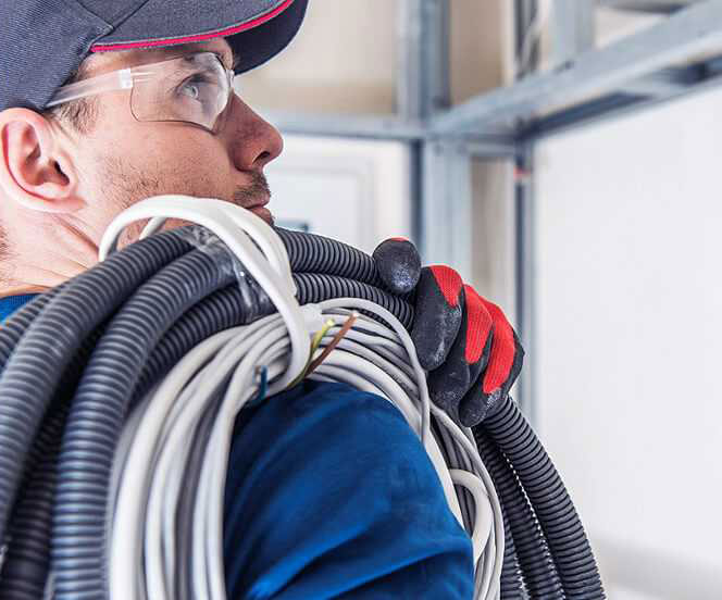 Electrician carrying coils of cable on site